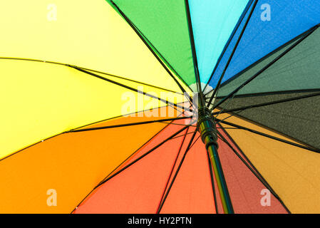 Multi farbige Schirm, die ihre Benutzer vor Regen unter dem Regenbogen farbige Segmente schützt Stockfoto