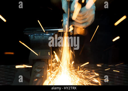 Arbeiter mit Mahlwerk schneiden und Schweißen von Metall mit vielen scharfen Funken in Fabrik Stockfoto