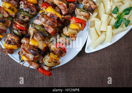 Gegrillte Fleischspieße - gegrilltes Schweinefleisch Kebab mit roten und gelben Paprika auf einem Teller mit Gemüse Stockfoto