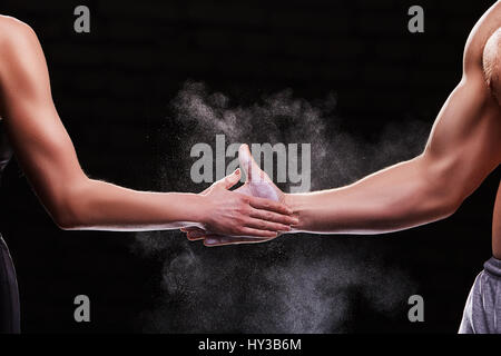 Zugeschnittenes Bild der Hände eines jungen Paares auf dunklem Hintergrund. CrossFit Fitness, Bodybuilding-Konzept Stockfoto