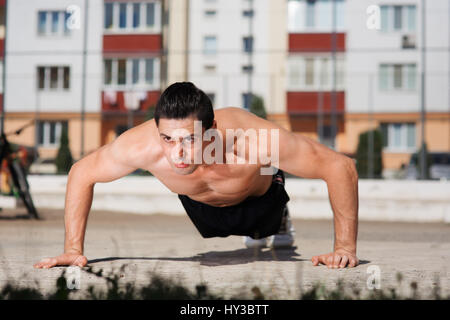 Niedrigen Winkel Ansicht eines Fit jungen Mannes Liegestütze auf dem Freigelände als Teil seiner täglichen Übung Regime zu tun. Stockfoto
