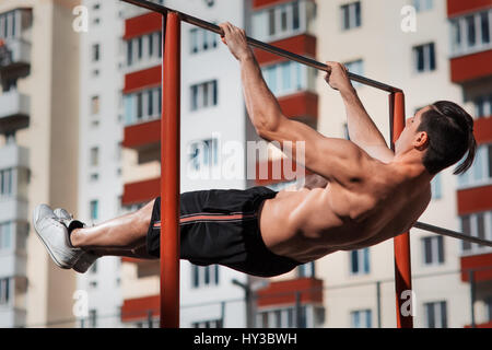 Passen junge Mann tut Push Ups auf horizontale Leiste im freien Stockfoto
