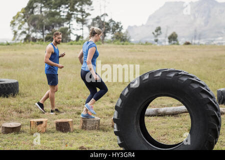 Fit Frau läuft auf hölzernen Maschinenbordbüchern während der Messzeit im Bootcamp trainer Stockfoto