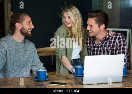 Fröhliche junge männliche und weibliche Freunde reden in Coffee-shop Stockfoto