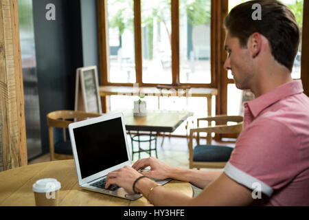 Seitenansicht der junge Mann mit Laptop am Tisch im Café Stockfoto