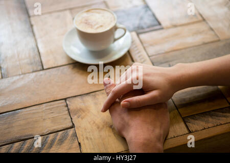 Bild von paar Hand in Hand mit Kaffeetasse am Tisch im Café beschnitten Stockfoto