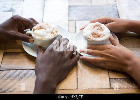 Hohen Winkel Nahaufnahme von Multi ethnischen paar Hände halten Kaffeetassen im café Stockfoto