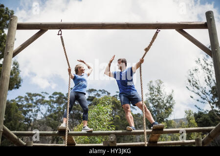 Passen Sie Mann und Frau geben hohe fünf während der Hindernis-Parcours mit Boot camp Stockfoto