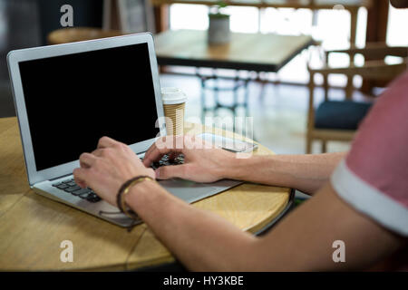 Bild von Mann mit Laptop am Tisch im Kaffeehaus beschnitten Stockfoto