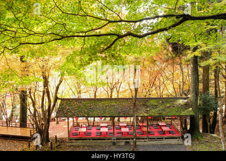 Traditionelle japanische Sitzgelegenheiten Restaurant mit roten Tische und schwarzen Kissen im Wald mit herbstlichen Farbe Bäume im Jingoji-Tempel in Kyoto, Japan Stockfoto