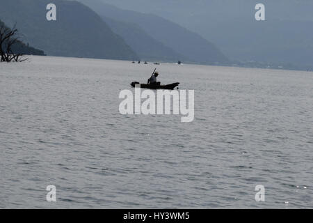 Fischer auf seine eigene Handarbeit gebaut Holzboot in See Lake Atitlan, Guatemala Stockfoto