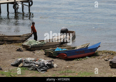 Junges Kind sieht seinem Vater bereitet ein Boot zum Fischen auf See Atitlan in Guatemala Stockfoto