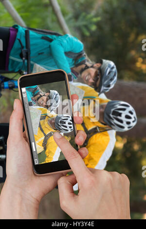 Hände berühren Smartphone gegen Biker paar Interaktion über Karte Stockfoto