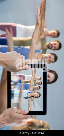 Beschnitten, Hand, die digital-Tablette gegen Lehrer Yogakurs teilnehmen Stockfoto