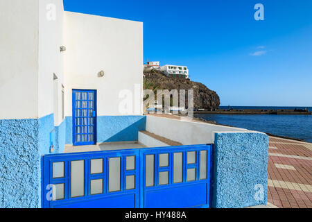 Blaues Tor und weißen Haus auf Promenade im Fischerdorf Las Playitas an der südlichen Küste von Fuerteventura, Kanarische Inseln, Spanien Stockfoto