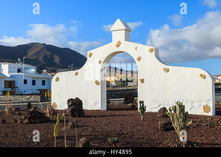 Typische Gemeinde melden (weißes Tor Bogens) in Gran Tarajal Dorf mit Wüstenlandschaft im Hintergrund, Fuerteventura, Kanarische Inseln, Spanien Stockfoto