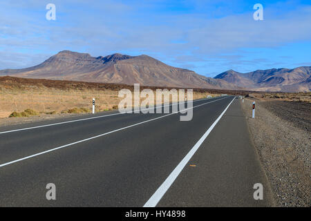 Straße in der Wüstenlandschaft und vulkanischen Bergen im Hintergrund, Fuerteventura, Kanarische Inseln, Spanien Stockfoto