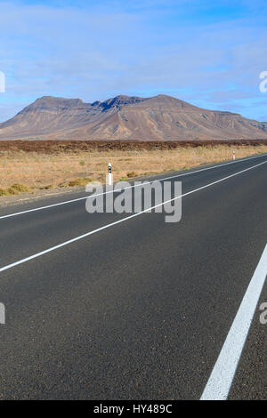 Straße in der Wüstenlandschaft und vulkanischen Bergen im Hintergrund, Fuerteventura, Kanarische Inseln, Spanien Stockfoto