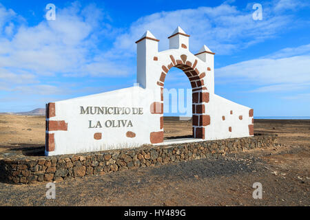 Typische Gemeinde La Oliva Village mit Wüstenlandschaft im Hintergrund, Fuerteventura, Kanarische Inseln, Spanien (weißes Tor Bogens) anmelden. Stockfoto