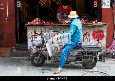 Lhasa, alte, Mann auf dem Moped vor Metzger Stockfoto