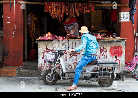 Lhasa, alte, Mann auf dem Moped vor Metzger Stockfoto