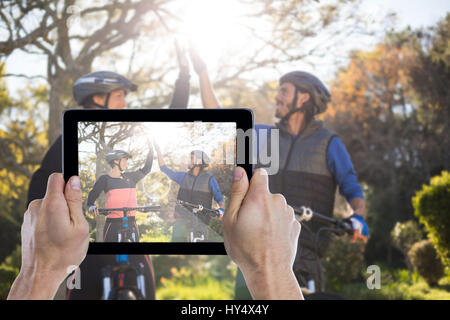 Hand, die digital-Tablette gegen Biker paar geben hohe fünf während der Fahrt Fahrrad im Lande beschnitten Stockfoto