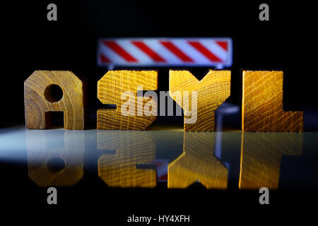 Das Wort Asyl aus Holz schreiben und sperren beamen, obere Grenze für Flüchtlinge, Das Wort Asyl aus Holzbuchstaben Und Sperrbalken, Obergrenze Fuer Fluec Stockfoto