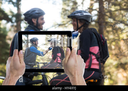 Hand, die digital-Tablette gegen Anpassung Fahrradhelm Frau Mann beschnitten Stockfoto