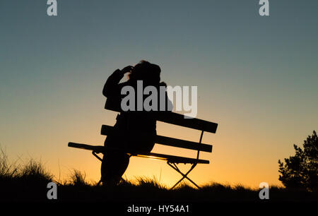 Silhouette einer Person sitzen auf einer Bank im Sonnenuntergang Stockfoto