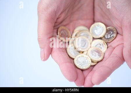 Pfund-Münzen halten in Händen Stockfoto