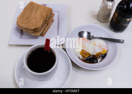 Traditionelles Frühstück in Singapur namens Kaya Toast, Kaffee Kokos Marmelade und halb gekochten Eiern, orientalische chinesische Kaffee Stockfoto