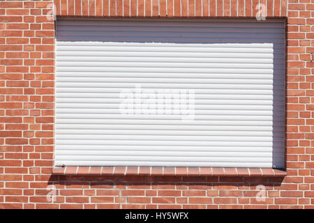 Windows mit geschlossenen Fensterläden auf einer roten Hauswand Stockfoto