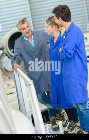 Drei Menschen stehen auf der Plattform neben Flugzeugen Stockfoto