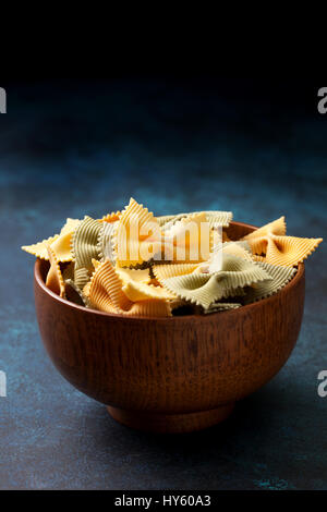 Traditionelle italienische Farfalle Nudeln in einer Holzschale auf blauem Hintergrund Stockfoto