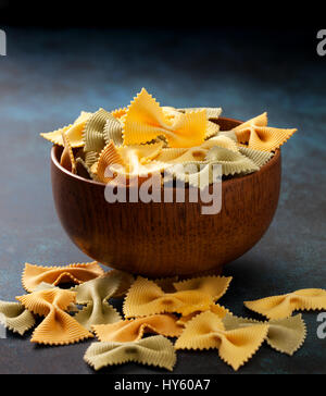 Traditionelle italienische Farfalle Nudeln in einer Holzschale auf blauem Hintergrund Stockfoto