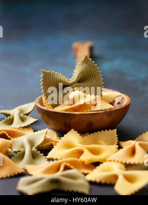 Traditionelle italienische Pasta Farfalle in einem Holzlöffel auf blauem Hintergrund Stockfoto