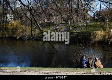 Besucher genießen eine starke Frühlingssonne am Ørstedsparken, einem Stadtpark Center in Kopenhagen, Dänemark Stockfoto