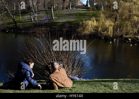 Besucher genießen eine starke Frühlingssonne am Ørstedsparken, einem Stadtpark Center in Kopenhagen, Dänemark Stockfoto