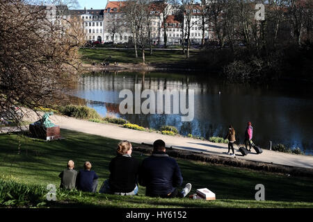 Besucher genießen eine starke Frühlingssonne am Ørstedsparken, einem Stadtpark Center in Kopenhagen, Dänemark Stockfoto