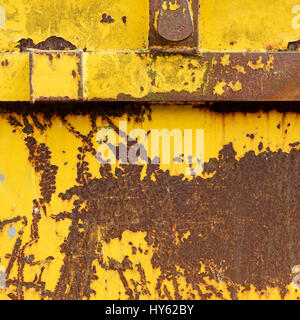 Altes rostigen Metall Container mit gelben läuten zerkratzten Lack und orange roten Buchstaben überspringen Stockfoto