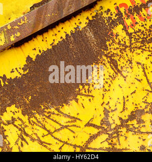 Altes rostigen Metall Container mit gelben läuten zerkratzten Lack und orange roten Buchstaben überspringen Stockfoto