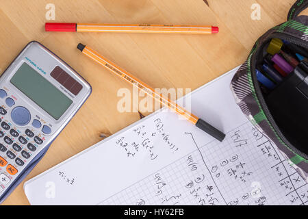 Ein Schulheft auf einem Schreibtisch mit Stiften und einen Taschenrechner Stockfoto