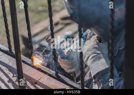 Ein Arbeiter Schweißen Metall Handläufe auf der Treppe. Schmiedeeiserne Geländer. Privathaus. Ukraine. Stockfoto