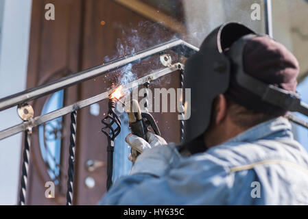 Ein Arbeiter Schweißen Metall Handläufe auf der Treppe. Schmiedeeiserne Geländer. Privathaus. Ukraine. Stockfoto