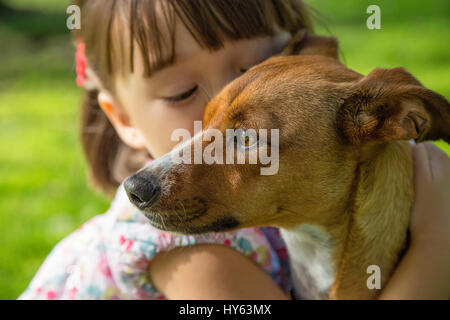 Kleinkind Mädchen umarmt ihren Hund in den Park, San Diego, Kalifornien Stockfoto