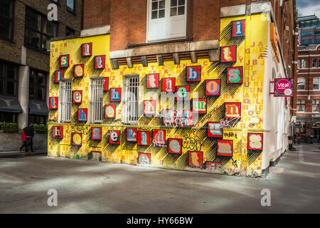 „Alphabet House“ Street Art von Ben eine – farbenfrohe Buchstaben auf einer gelben Wand in Spitalfields, London, England, Großbritannien Stockfoto