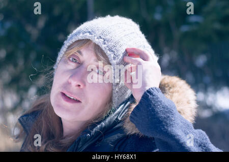 Frau trägt Wollmütze und warme Kleidung posiert in einem sonnigen Wintertag Stockfoto