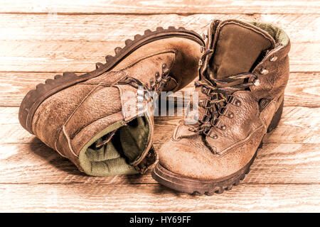 ein paar alte, ausgetretene, Wanderschuhen auf verwittertem Holz, retro Sepia Tönung Stockfoto