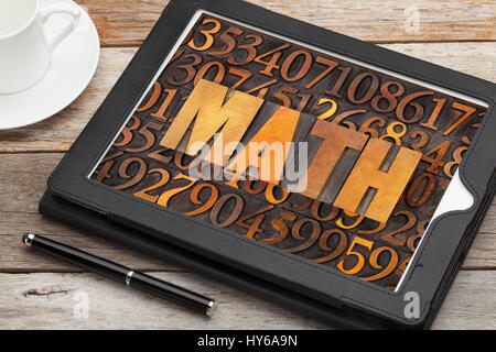 Mathematik (Mathematik) Wort in Vintage Buchdruck Holzart Nummer Hintergrund auf einem Tablet-Bildschirm mit einer Tasse Kaffee Stockfoto