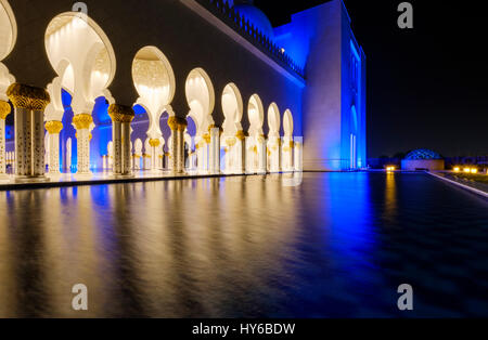 Vereinigte Arabische Emirate, ABU DHABI - ca. Januar 2017: Pool, Bögen und Säulen der Sheikh-Zayed-Moschee in der Nacht. Stockfoto